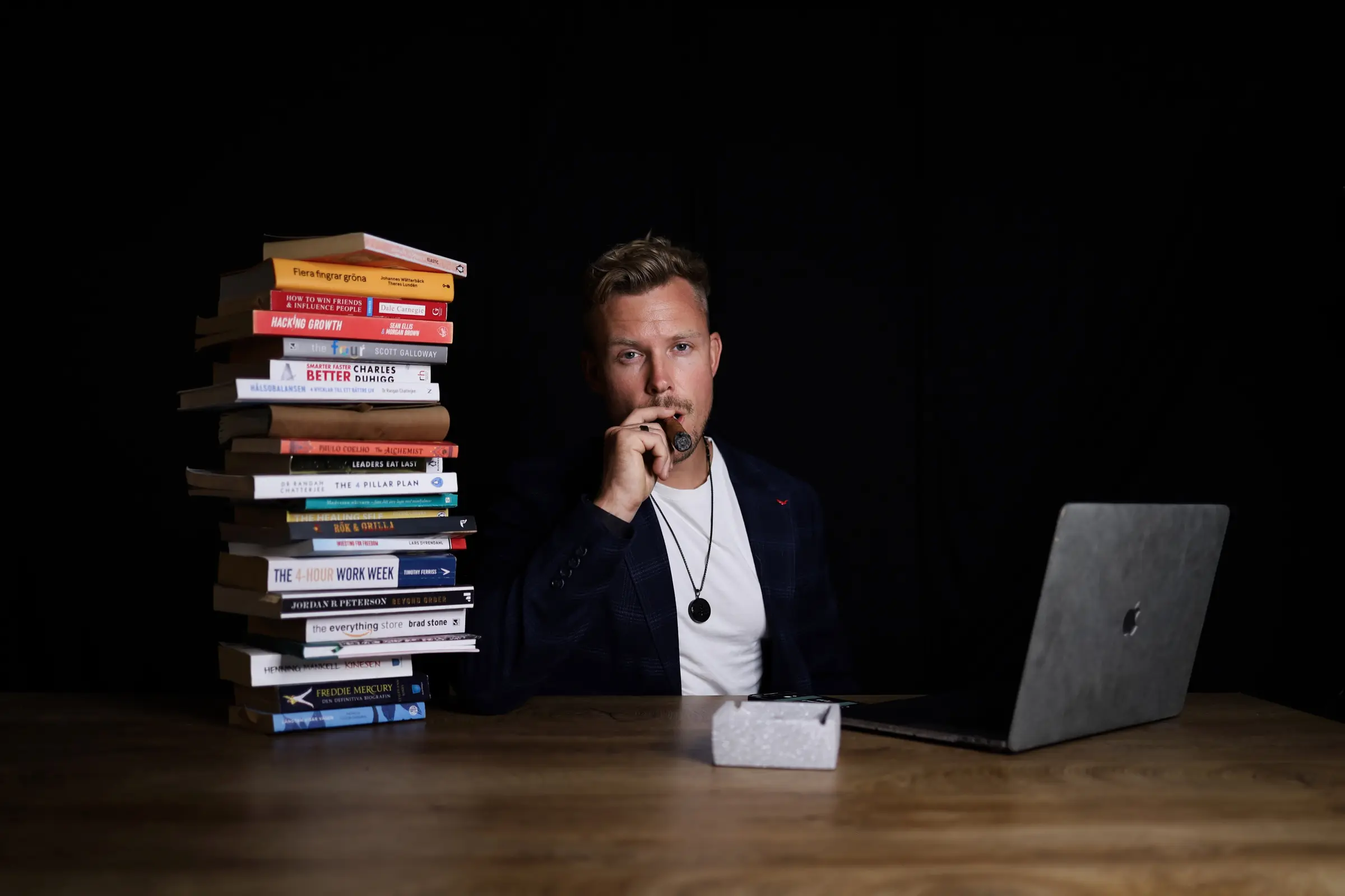 John Talasi at his desk beside a stack of books